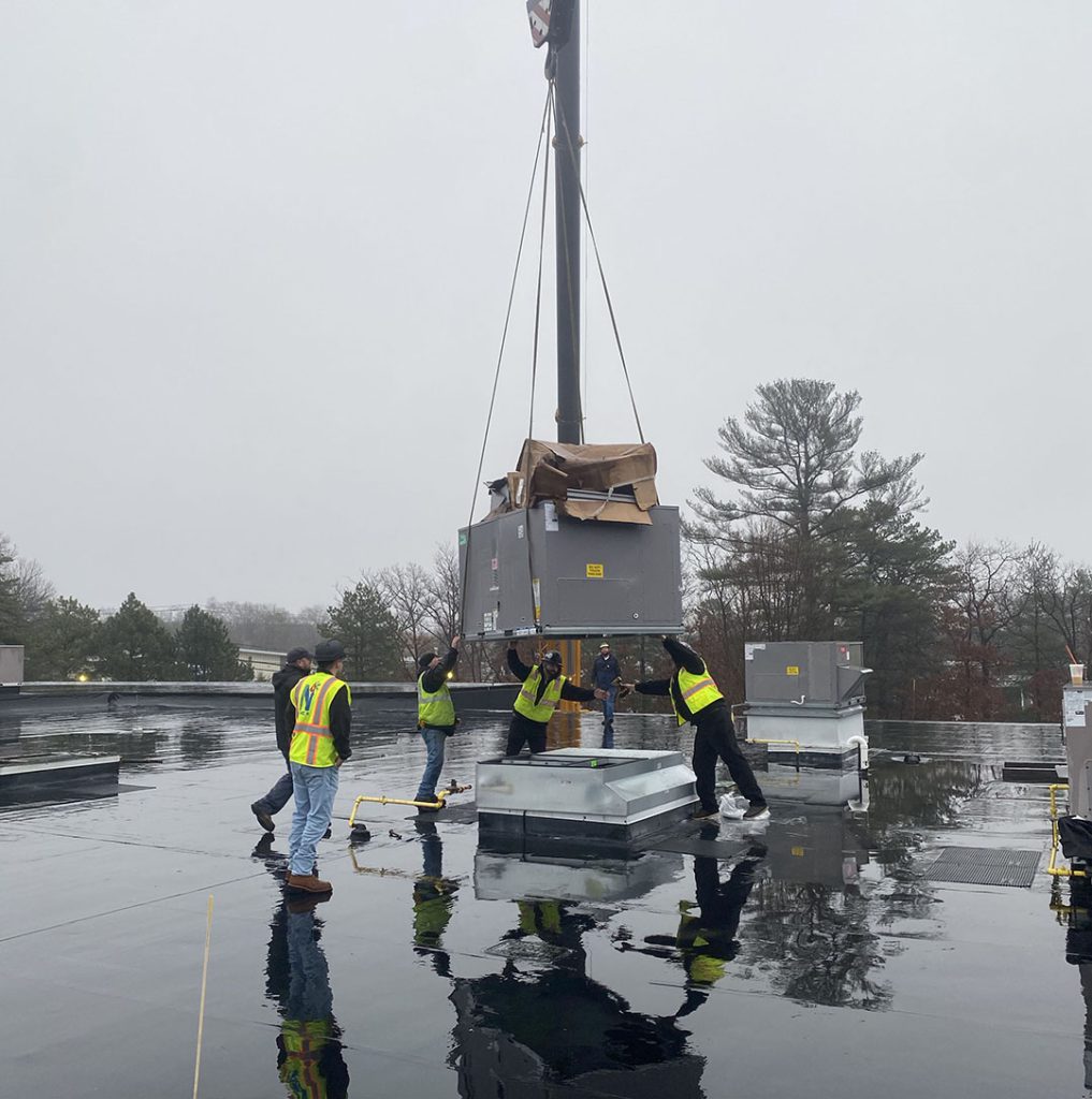 Crew guides a new rooftop unit into position at Tech Etch in Plymouth, Massachusetts.