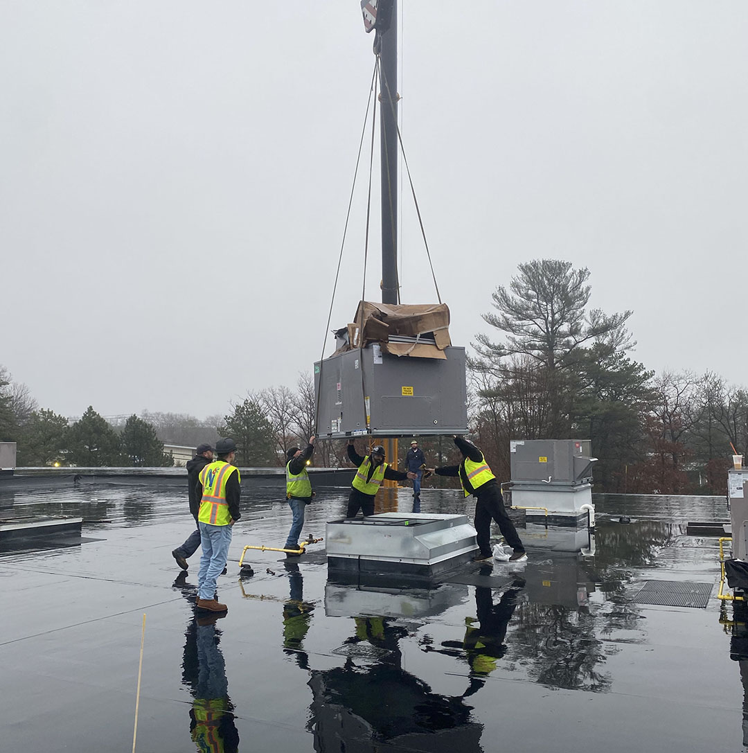 Crew guides a new rooftop unit into position at Tech Etch in Plymouth, Massachusetts.