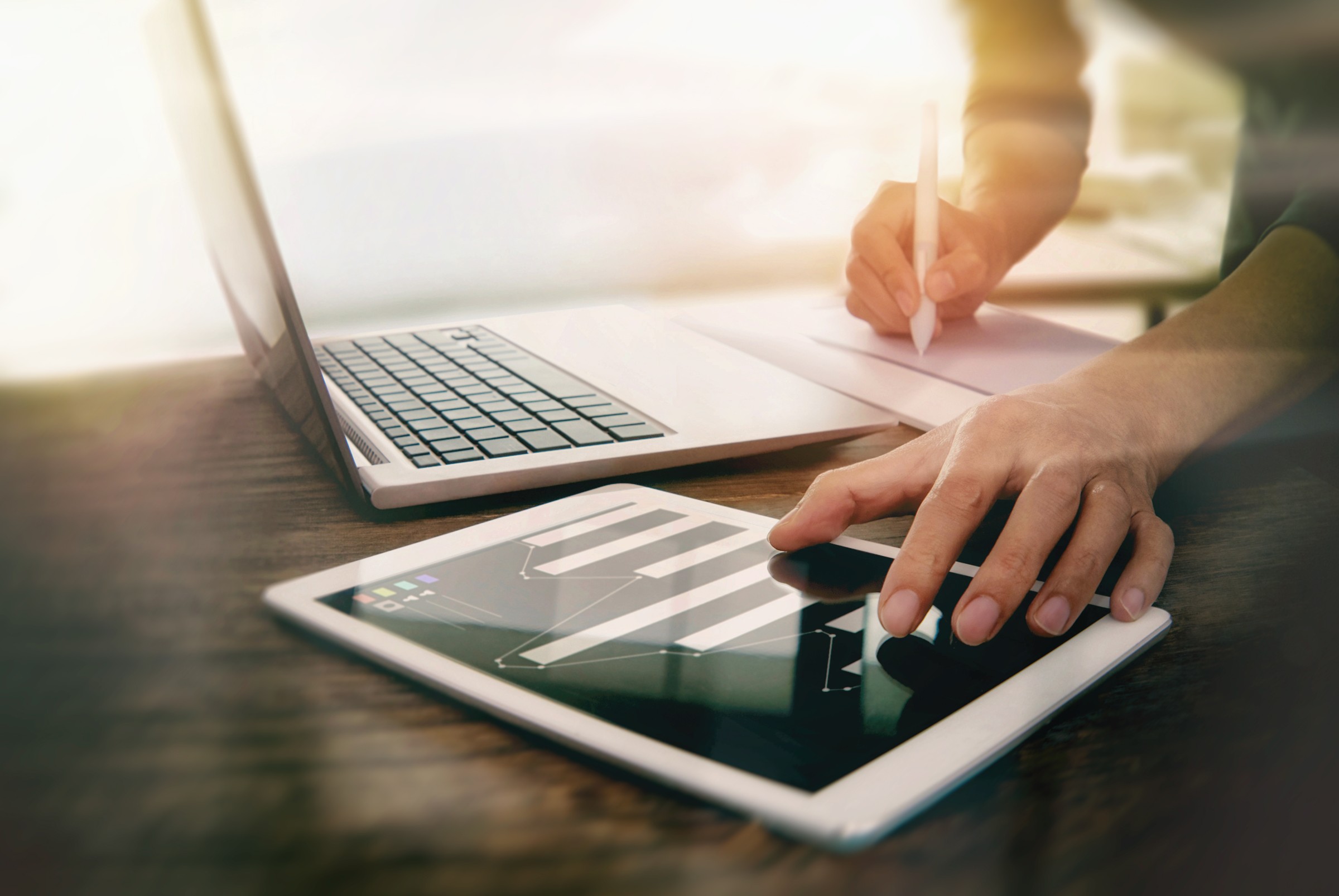 Hands reviewing information on a laptop and tablet