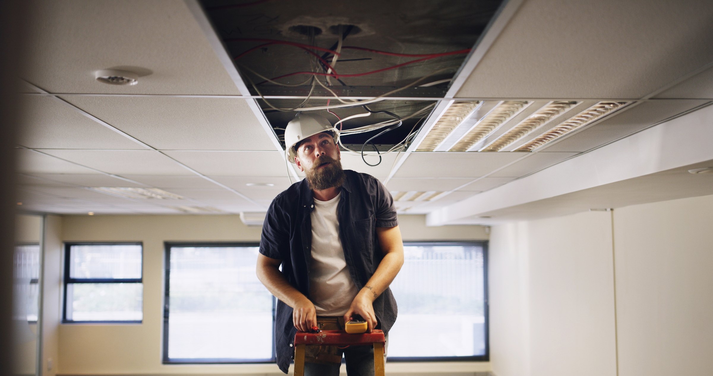 Electrician working beneath an open ceiling