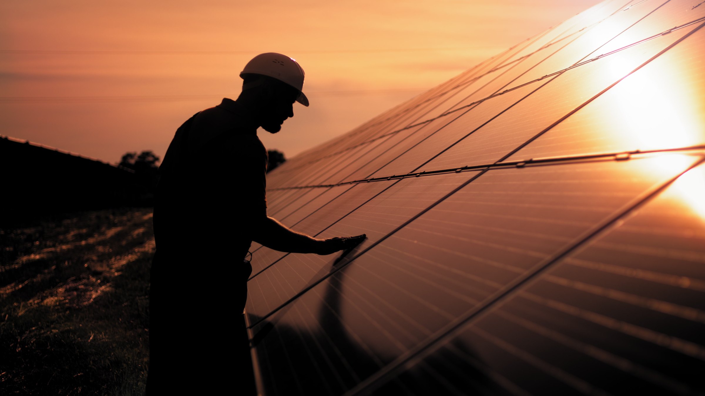 Worker maintaining solar panels at sunset